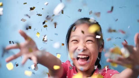 Happy Asian girl celebrating with silver and golden papers glitter falling down