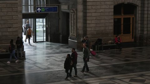 Antwerp, Belgium - April 1, 2019: Beautiful view of many people with suitcases strolling inside of shadowy train station in Antwerp in spring in slow motion. It looks European