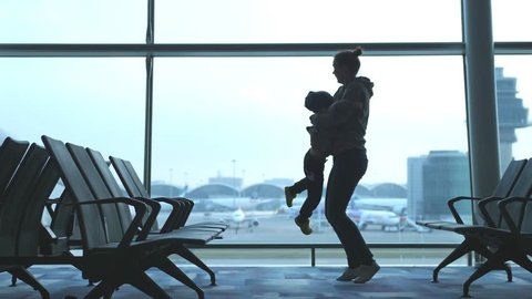 Mother embracing son and spinning around loving family waiting for flight. slow motion. 3840x2160. 4k
