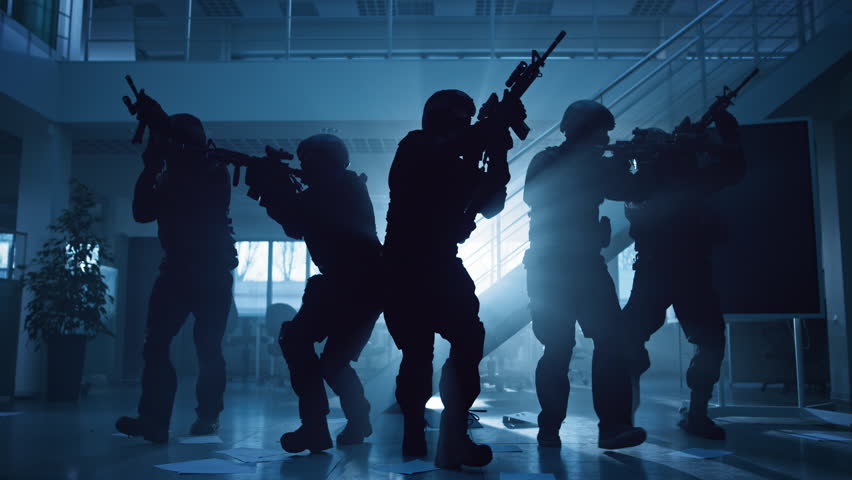 Masked Fireteam of Armed SWAT Police Officers Storm a Dark Seized Office Building with Desks and Computers. Soldiers with Rifles Move Forwards and Cover Surroundings.