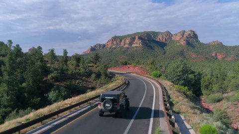 Sedona, AZ / USA - June 4, 2017: Sedona Jeep Driving Through Arizona Desert Highway, Aerial Drone Shot of Sedona Mountain Landscape