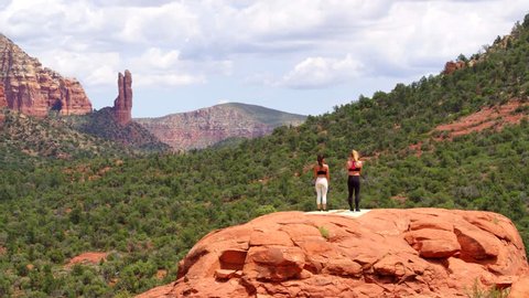 Two Women Doing Yoga on top of Red Rocks in Sedona, Arizona Desert Mountain Landscape by Flying Aerial Drone Shot