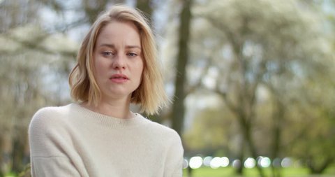 Disturbed woman with tears in her eyes outside in park
