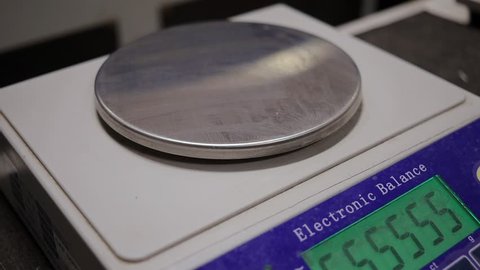 A technician weighs a sample of cardboard using a electronic balance for quality control