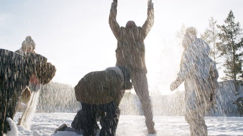 Three shot sequence of young family of seven having fun during countryside walk on bright sunny day, tossing up sparkling snow and throwing snowballs, with excited kids jumping around and laughing