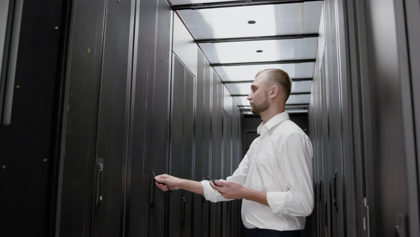Caucasian man open server rack and checking data center slow motion. Serious system administrator looking to mining farm and diagnostic cloud infrastructure standing before the modern datacenter Royalty-Free Stock Footage #1028554406