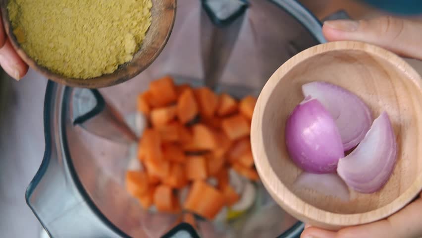 Female Hands Add Nutriotional Yeast and Red Onion into Blender to Cook Vegetable Sauce. Top View, Vegan and Vegeterian Food. Lifestyle of Health and Sustainability Concept