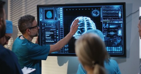 Medium shot of a doctors discussing brain damage diagnosis at a digital screen with a 3D image of a brain