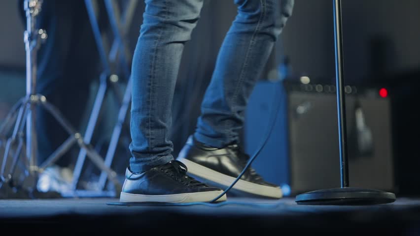 Soloist on stage, rock music. Musician stomps foot during concert