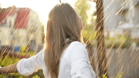 Beautiful Woman With Wet Hair Enjoying the Rain And Looking Up To the Sky. Pretty Woman in Summer Garden Having a lot of Fun. Happy Rainy Day. Colorful Video in Warm Colors. Leaves With Rain Drops.