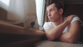 man sad bored riding a train railway looks out the window. traveler concept train railroad journey travel. slow motion video. beautiful from window of a moving train railway trip Russia winter