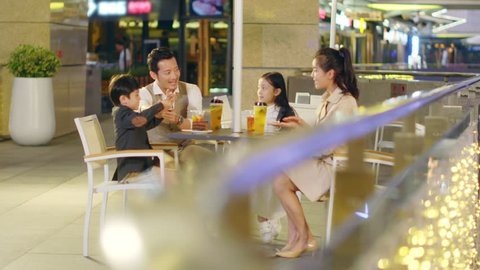 happy asian family with two children chatting relaxing at a coffee place