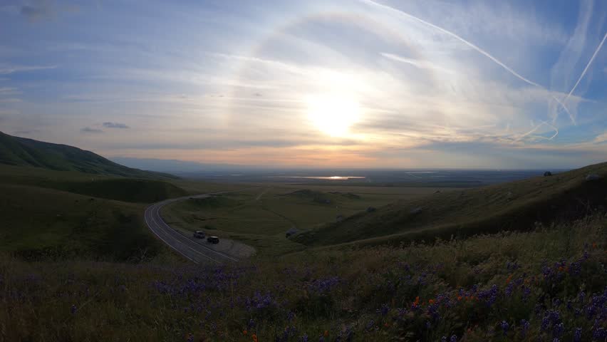 Spectacular Sunset Timelapse with Wispy Clouds over Winding Road and Green Hills