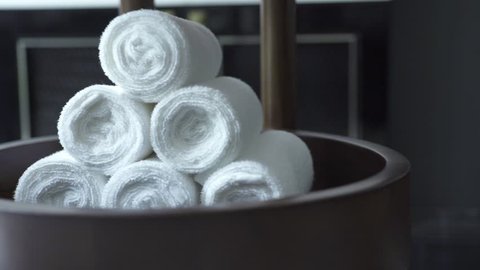 White towel roll in modern spa salon on dark background. White bath towel in dark bathroom. Accessories for shower, spa sauna, swimming pool and bath
