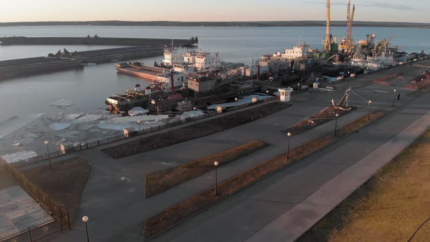 flight over the river port at sunset time, mooring of construction barges and ships, aerial filming