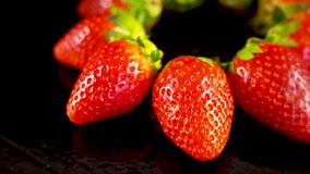 Nice fresh red strawberrys rotating on black surface. Sweet 4k fruit footage.