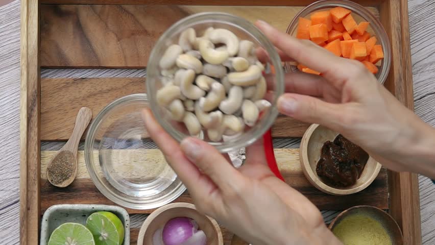 Female Hands Taking Cashew Nuts from Tray. Top View. Vegan and Vegeterian Food. Lifestyle of Health and Sustainability Concept