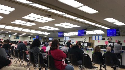 LOS ANGELES, APR 25th, 2019: People sitting on chairs inside the busy waiting room area at the Department of Motor Vehicles DMV field office building in Culver City, California. With ambient sound.