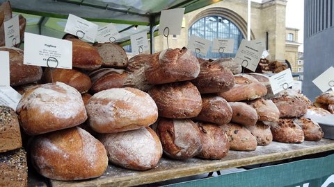 KINGS CROSS, LONDON - MARCH 20, 2019: Piles of freshly baked artisan bread loaves on sale at a food market stall outside Kings Cross Train Station in London, UK. 