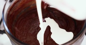 Close up clip of double cream being added to melting chocolate in double boiler water bath bain-marie while stirring with a wooden spoon dessert Sequence 3 of 4 4K 30 fps