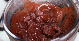 Closeup clip of melting cooking chocolate in double boiler water bath bain-marie being stirred with a wooden spoon Sequence 1 of 4 4K 30 fps