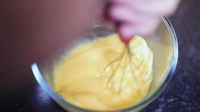 Lady stirring eggs in a clear glass bowl as a preparation for a delicious ham and cheese omelet in slow motion clip 1080p 120 fps