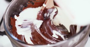 Closeup clip of melting dark, milk, and black chocolate in double boiler water bath bain-marie being stirred with a wooden spoon 