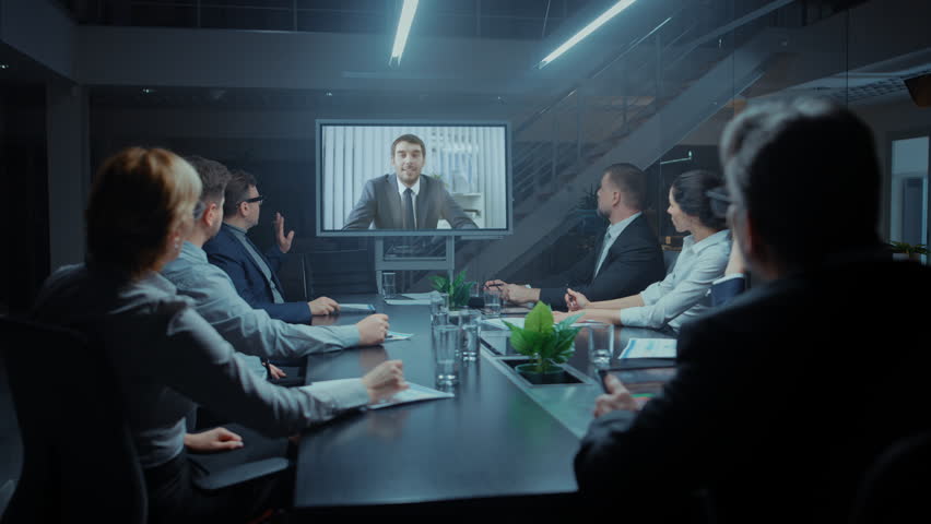 In the Conference Room Group of Directors, Investors and Businessmen Making Late Night Video Conference Call To Talk with International Corporation Representative Royalty-Free Stock Footage #1028612192