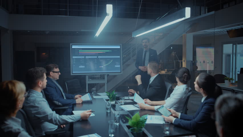 In the Corporate Meeting Room: Male Executive Talks and Uses Digital Interactive Whiteboard for Presentation to a Board of Directors, Investors. Screen Shows Growth Data. Late at Night Office Royalty-Free Stock Footage #1028612204