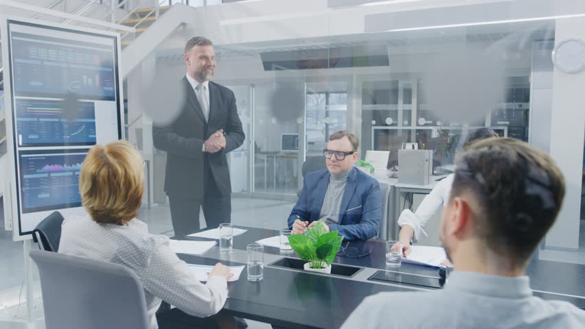 In the Corporate Meeting Room: Enthusiastic Director Uses Digital Interactive Whiteboard for Presentation and Delivers Powerful Speech to a Board of Executives. Everybody Cheers and Applauds Royalty-Free Stock Footage #1028612291