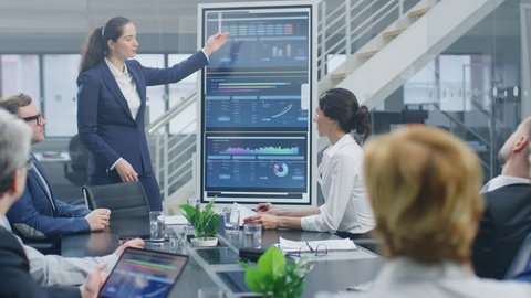 In the Corporate Meeting Room: Young and Talented Female CEO Uses Digital Interactive Whiteboard for Presentation and Delivers Powerful Speech to a Board of Executives, Lawyers, Investors