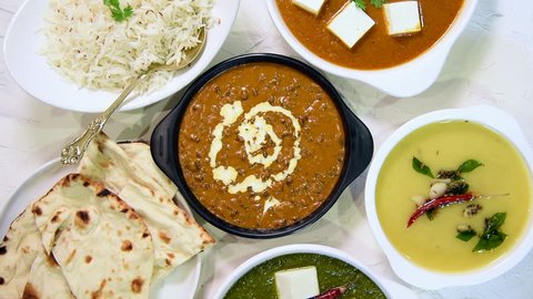 Indian vegetarian  platter / Thali having Palak paneer butter masala, dal makhani, flat bread or naan and rice served in a white plate