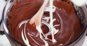 Closeup clip of melting dark, milk, and black chocolate in double boiler water bath bain-marie being stirred with a wooden spoon 2