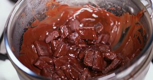 Speed up closeup clip of melting dark, milk, and black chocolate in double boiler water bath bain-marie being stirred with a wooden spoon 4K 30 fps