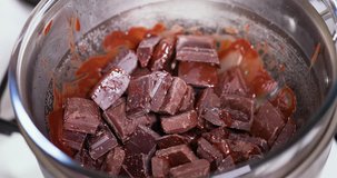 Closeup clip of melting dark, milk, and black chocolate in double boiler water bath bain-marie being stirred with a wooden spoon 4K 30 fps