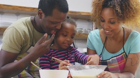 Close up of funny African family in kitchen cooking and tasting dough