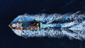 Aerial top view video of big traditional fishing boat cruising in deep blue sea near port of Paros island at sunset, Cyclades, Greece