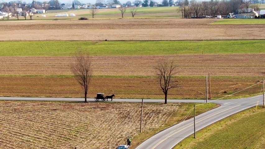 Aerial at a distance an Amish horse and buggy trotting across the intersection of two rural roadways, Lancaster County, ?Pennsylvania. Concept: traditional transportation, Amish,lifestyle