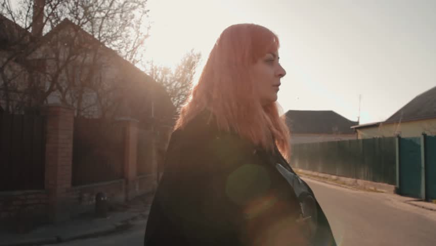Portrait of young girl with pink hair posing in front of the camera at the street at sunny day