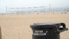This slow motion video shows a young fit caucasian woman throwing away trash at the beach.
