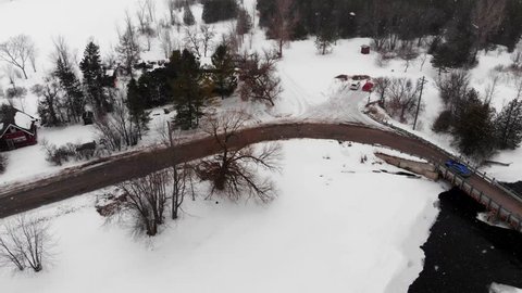 Aerial, drone shot, of a car driving on a slushy road, near Blakeney rapids, at snowfall, on a winter day, in Mississippi Mills, Ontario, Canada