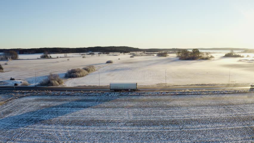 fields and road at sunset - frozen mist during winter in sweden - aerial