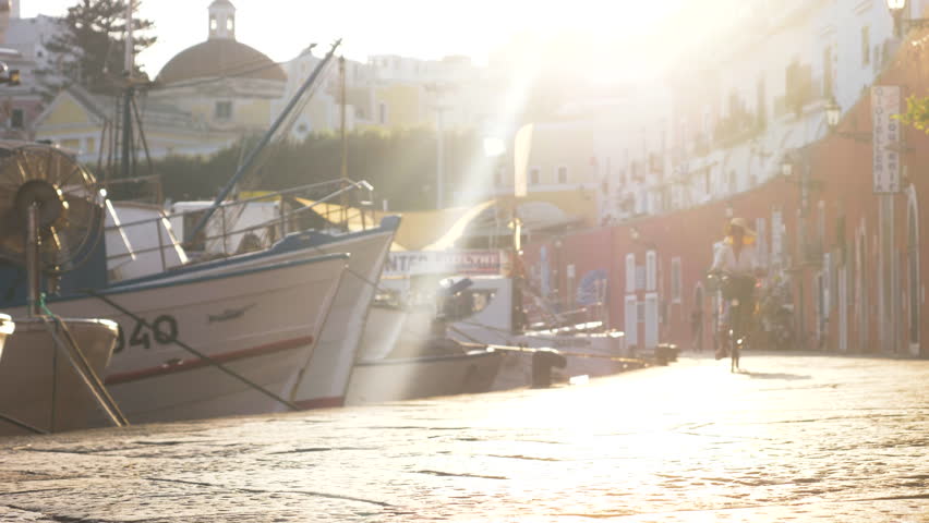 Happy young woman walking with vintage bike along the harbour in Ponza island Italy. Fashion colorful dress skirt and hat.