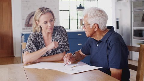 Woman Helping Senior Man To Complete Last Will And Testament At Home