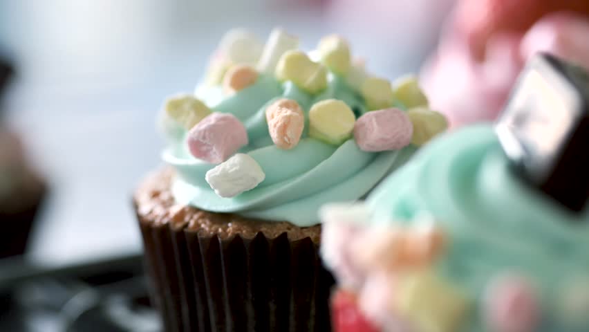 Green cupcakes with mashmellows on table, slow motion.