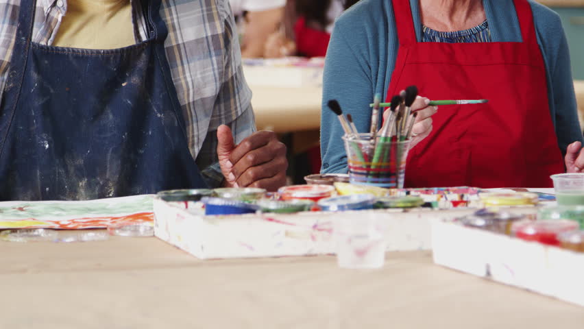 Group Of Retired Seniors Attending Art Class In Community Centre With Teacher