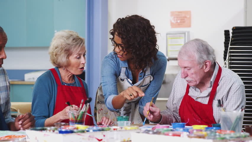 Group Of Retired Seniors Attending Art Class In Community Centre With Teacher