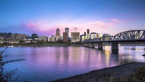 Night to day time-lapse video of modern Portland skyline with historic Hawthorne bridge reflecting in famous Willamette river on a beautiful summer morning with blue sky and moving clouds, Oregon, USA