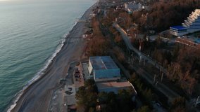 Aerial video shooting. Panoramic view of the black sea coast of Sochi. Sunset over the sea and mountains. Camera's moving backwards. Beautiful blue sky with clouds