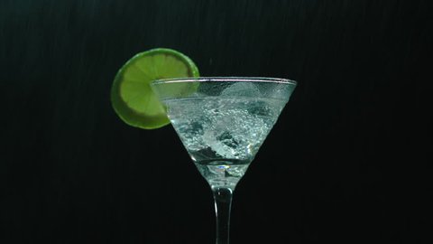 Rotating martini glass sprayed with a water can creating a cool rain effect. Promotional product video for an event or a beverage.